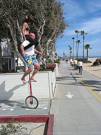 They're off! Julie sitting on Eric's shoulders, while he rides his unicycle at the strand, Balboa Peninsula, Newport Beach, California