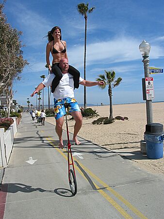 Here they come: Julie sitting on Eric's shoulders, while he rides his unicycle down the strand, Balboa Peninsula, Newport Beach, California