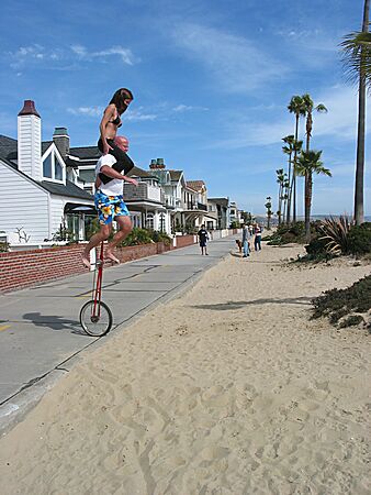 Eric prepares to dismount his unicycle, by landing inn the soft sand, at the strand, Balboa Peninsula, Newport Beach, California